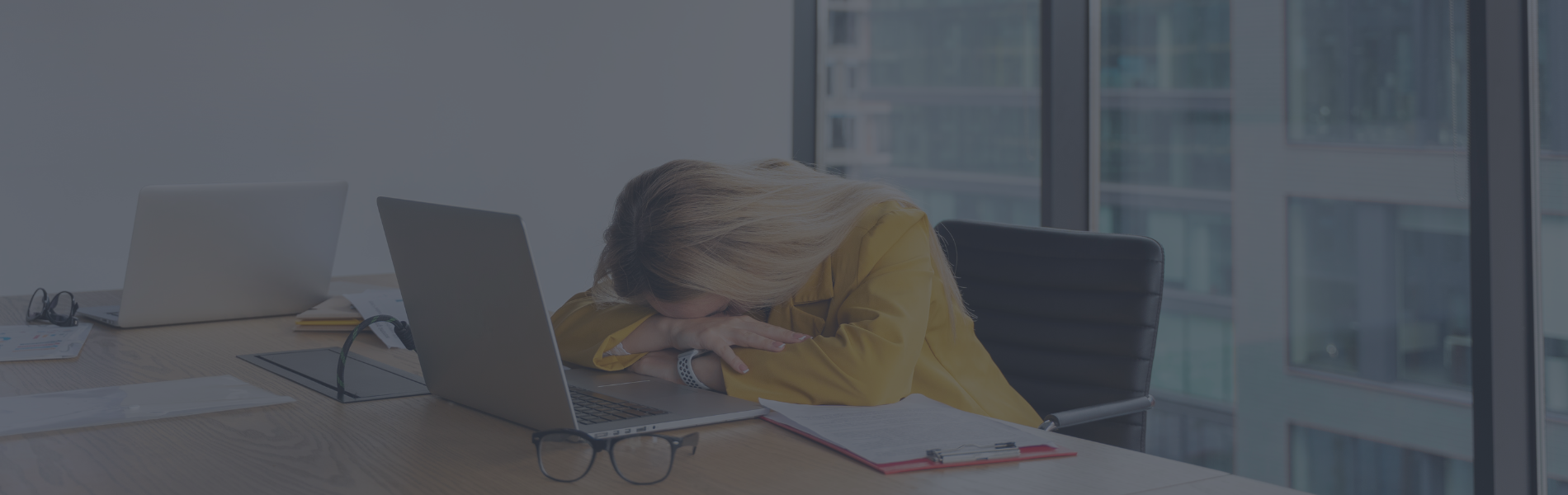 Woman suffering from imposter syndrome at work and putting her head in her hands at her laptop.