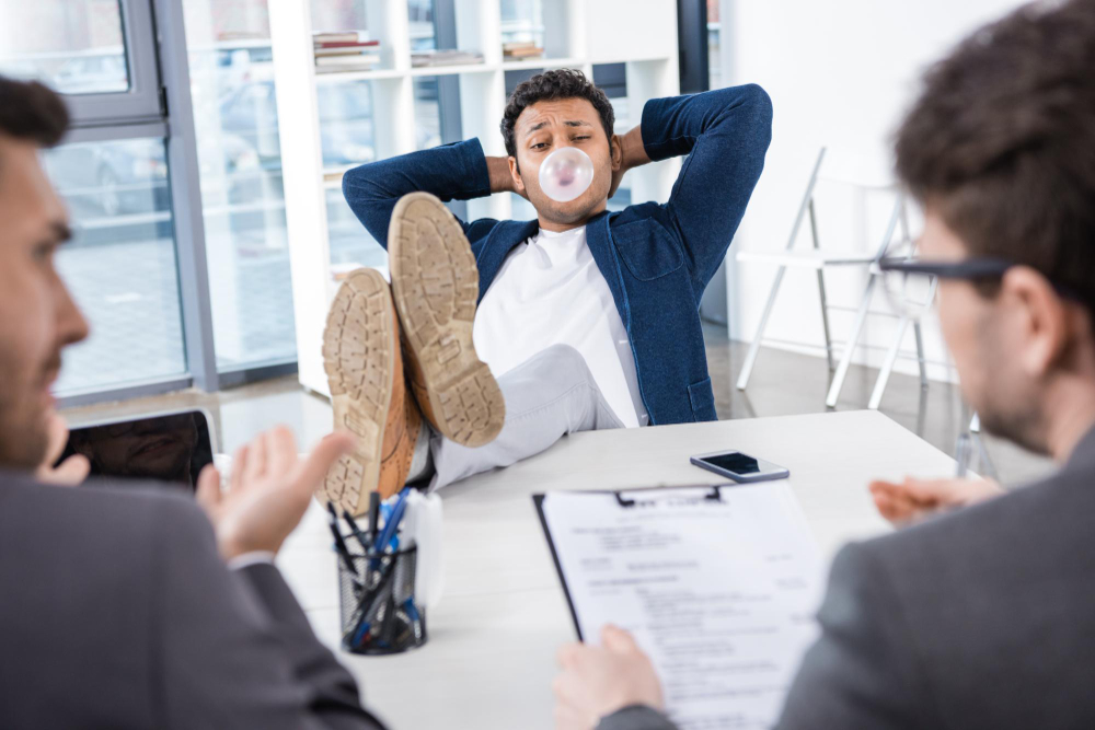 Businessman blowing bubble gum with legs on table during job interview